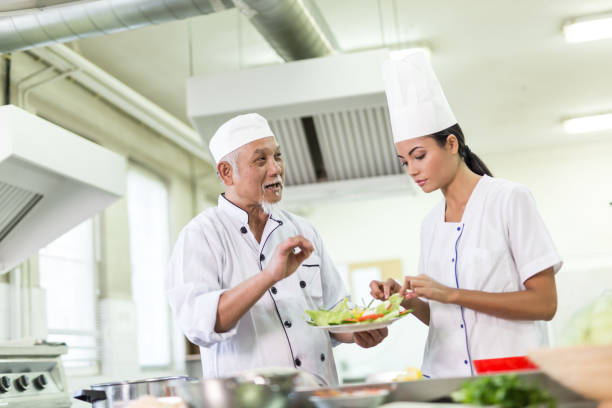 istock Chef teaching a trainee to prepare asian food 871625168