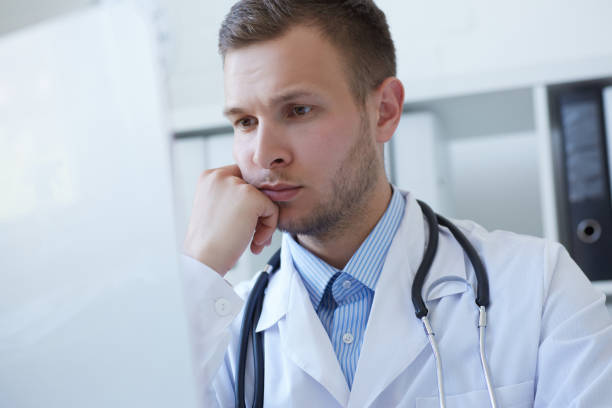 istock Young male doctor using computer on desk in clinic. 871625864