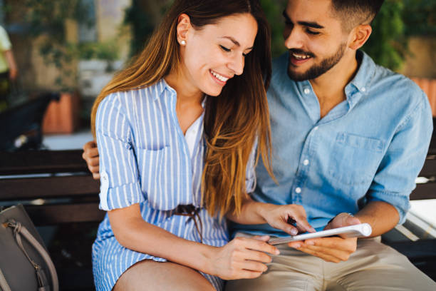 istock Young attractive couple on date sitting on bench 871629056