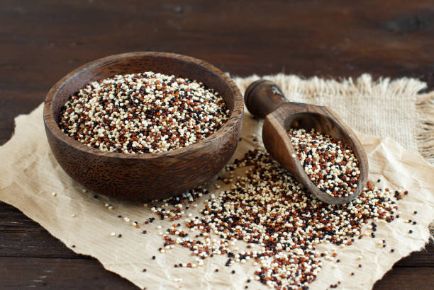 uncooked mixed quinoa grain in a bowl - quinoa spoon wood photography imagens e fotografias de stock
