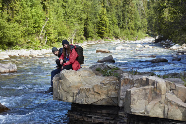 istock Couple resting on a rock above river 871644288