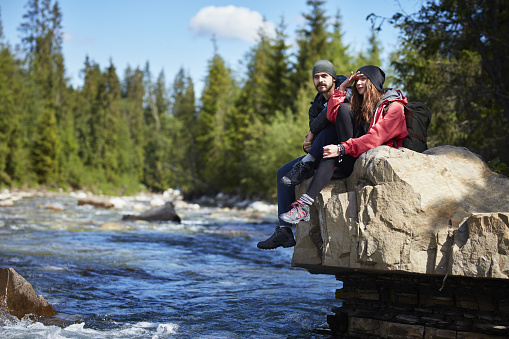 Young couple resting after hike. Mountainous landscape