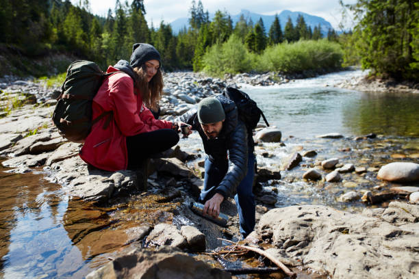 istock Couple crossing the river in mountains 871647802