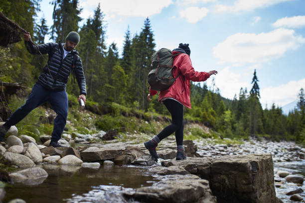 istock Couple crossing the river in mountains 871648170
