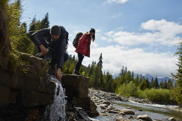 istock Couple crossing the river in mountains 871648200