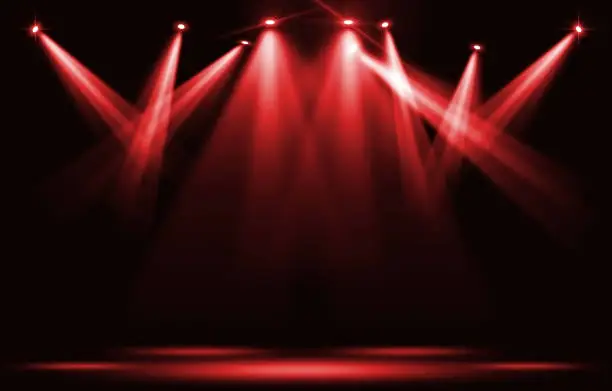 Photo of Stage lights. Red spotlight strike through the darkness.