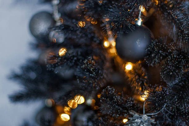 istock Christmas dark blurred background with a black Christmas tree, ornaments and bokeh lights 871656398