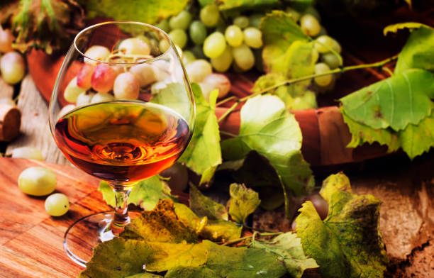 Cognac In Glass, Grapes And Vine Cognac In Glass, Grapes And Vine, Vintage Wood Background, Selective Focus cognac brandy stock pictures, royalty-free photos & images