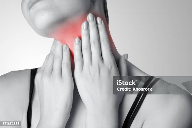 Closeup View Of A Young Woman With Pain On Neck Or Thyroid Gland On Gray Background Stock Photo - Download Image Now