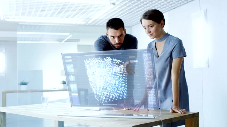 In the Near Future Male and Female Computer Engineers Talk While Working on the Transparent Display Computer. Screen Shows Interactive Neural Network, Artificial Intelligence Project, Futuristic User Interface.