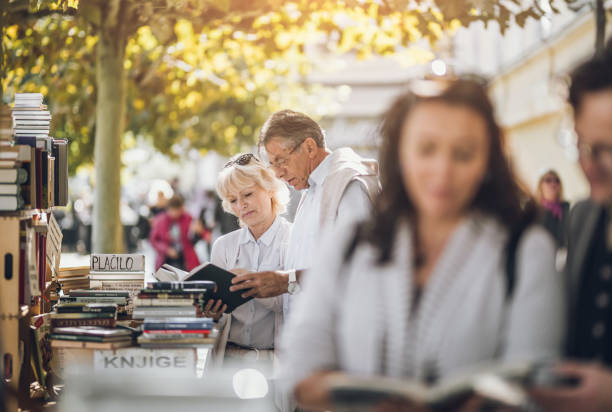 istock Mature Couples Looking at Books on Street 871680178