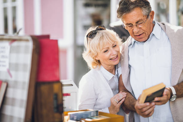 istock Mature Couples Looking at Books on Street 871680186