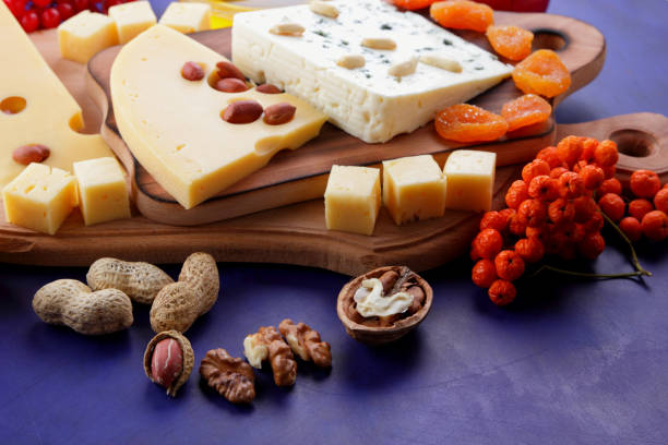 istock Various cheeses, apple, dried apricots, peanuts, walnuts, pears, berries, honey, jam, cheese with a mold on a wooden board in the style of pop art and retro style, Christmas cheese 871692526