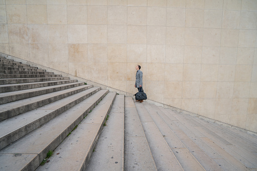 Profile shot of a businessman walking stairs up to work in the city of Paris.