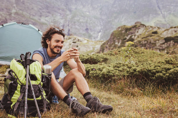 Camping and communication Young tourist resting in the mountain and text messaging extreme terrain stock pictures, royalty-free photos & images