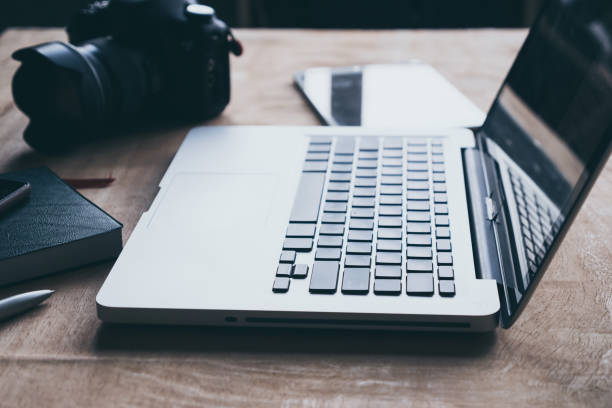 istock Laptop with tablet and camera on wooden table. 871695248