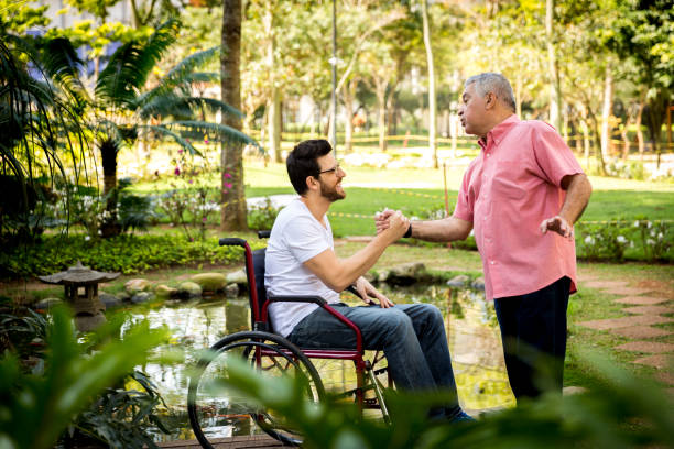 istock Dad helping his son sitting in his wheelchair 871704264