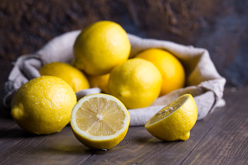 Group of fresh ripe lemon in sackcloth on an old vintage wooden table