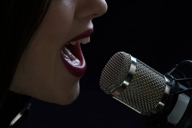 istock Singer in front of a microphone. Isolated on a dark background 871711472