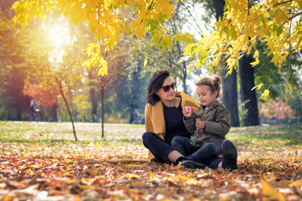 istock Mother and daughter blowing bubbles in autumn park. 871717456