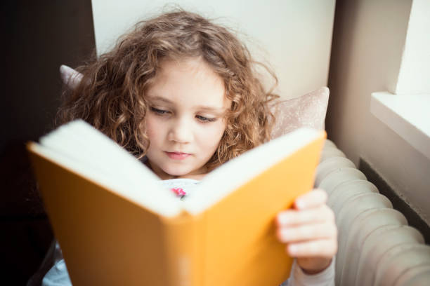 istock little girl read a book at the window 871719948