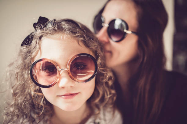 A mother and her daughter with sunglasses in the living room.