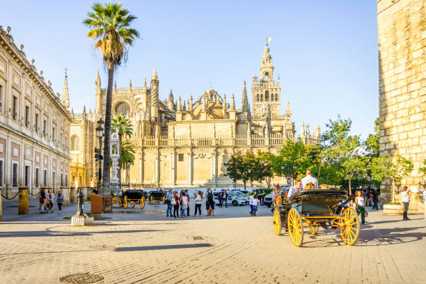 Cathedral of Saint Mary of the See with tourists, Seville, Spain Cathedral of Saint Mary of the See with horse carriage, Seville, Spain alcazar seville stock pictures, royalty-free photos & images