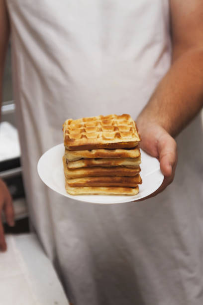 un montón de obleas recién horneados en las manos del chef para los hombres, primer plano, retro tonificación - brussels waffle belgian waffle people fotografías e imágenes de stock