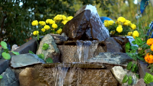 Artificial waterfall in the park, water runs along the stone steps, slow motion