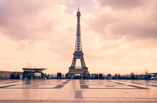 Eiffel tower, Paris symbol and iconic landmark in France, on a cloudy day. Famous touristic places and romantic travel destinations in Europe. Cityscape and tourism concept. Long exposure. Toned.