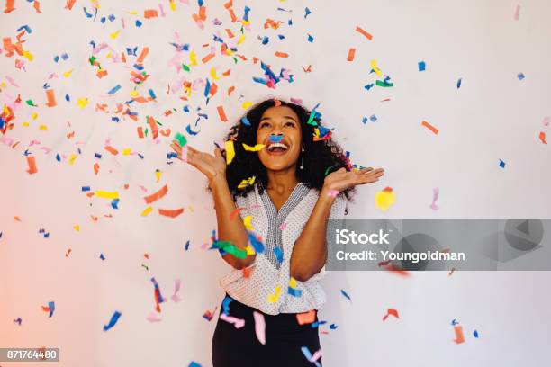 Photo libre de droit de Jeune Femme Debout À Lintérieur Sous Les Confettis Colorés banque d'images et plus d'images libres de droit de Festivité