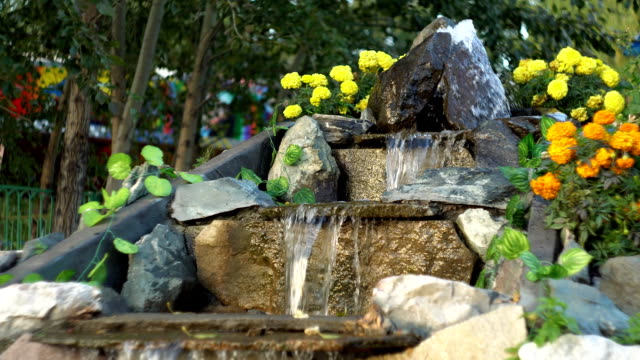 Artificial waterfall in the park, water runs along the stone steps