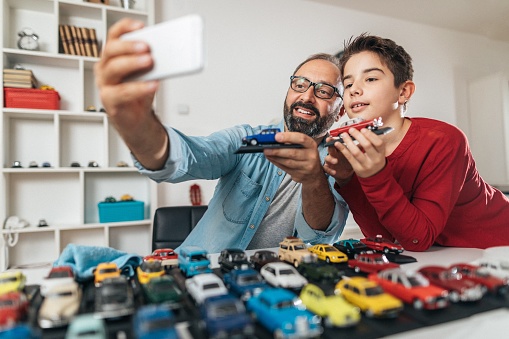 Photo boy with his father takes selfie with favorite toys