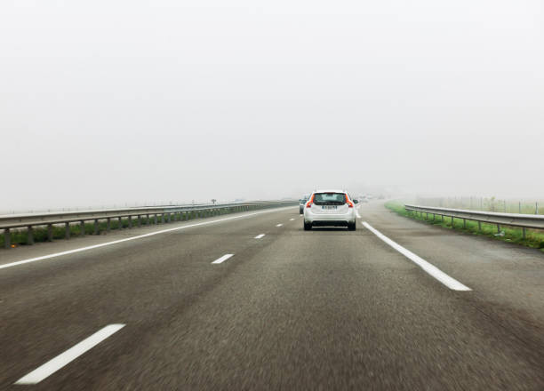 Frankfurt: Rear view of white Volvo V60 car driving on German autobahn - fast motion in safety condition during heavy mist