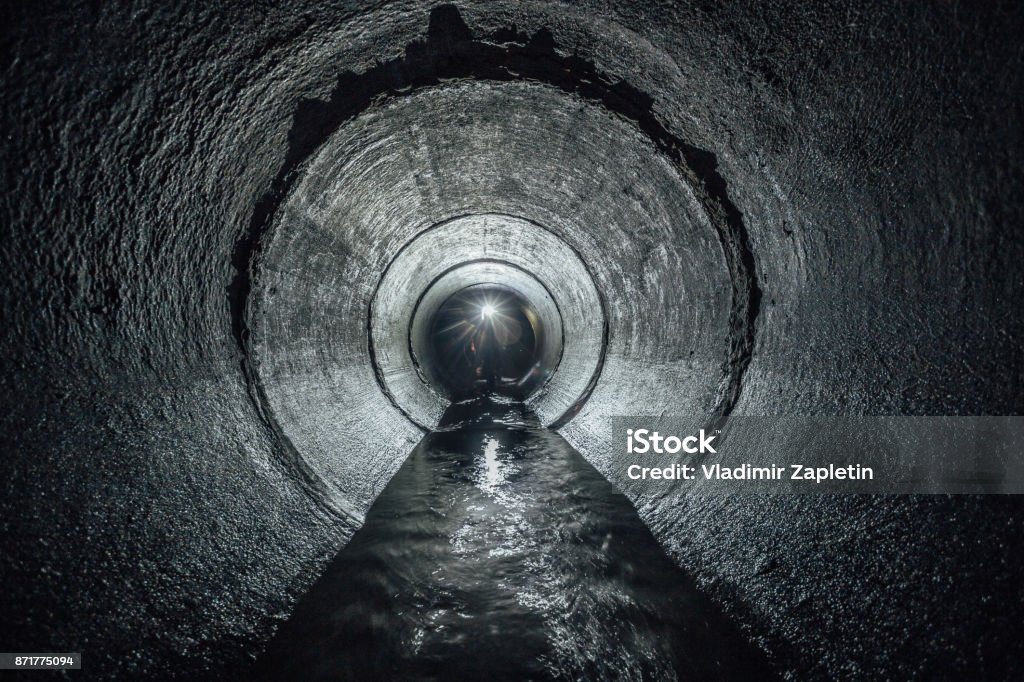 Fiume sotterraneo che scorre in un tunnel di fognatura in cemento rotondo. Collettore fognario - Foto stock royalty-free di Liquami