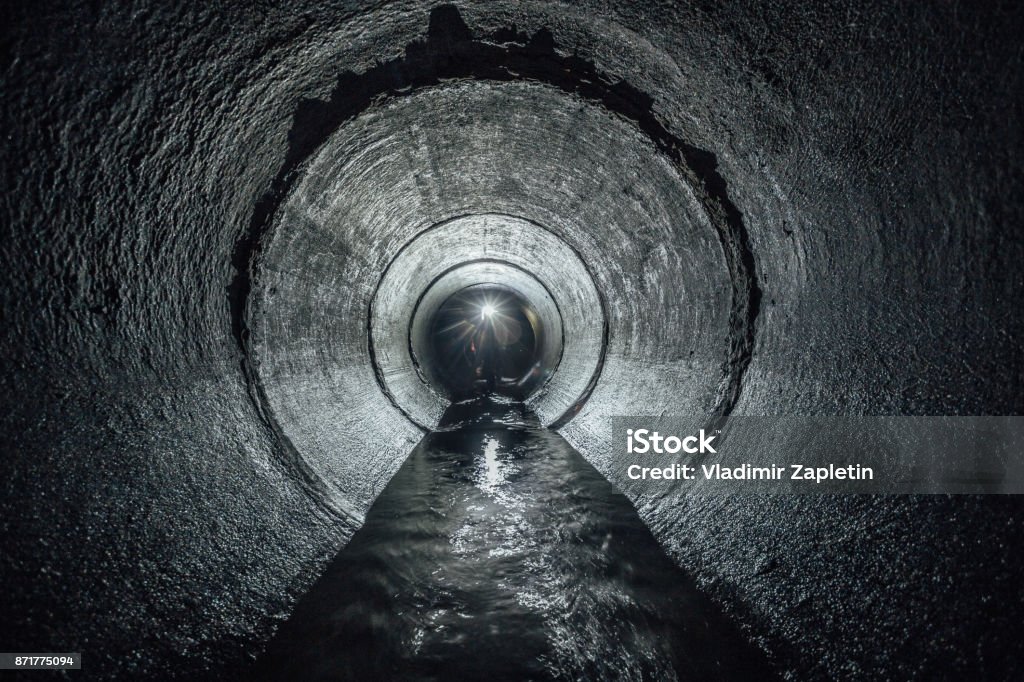 Underground river flowing in round concrete sewer tunnel. Sewage collector Underground river flowing in round concrete sewer tunnel. Sewage collector. Sewage Stock Photo