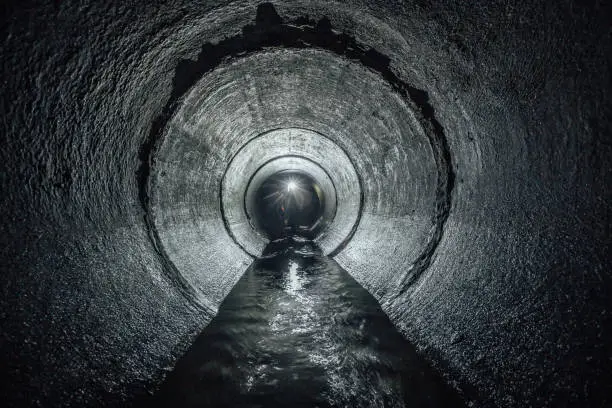 Photo of Underground river flowing in round concrete sewer tunnel. Sewage collector