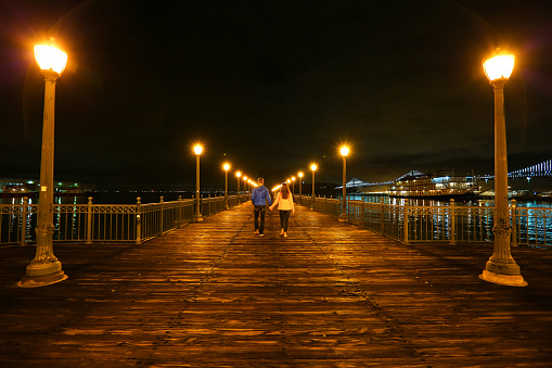 streetlights along a pier and a couple holding hands.