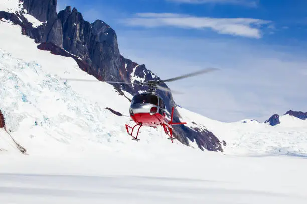 A helicopter landing on a remote mountain glacier.