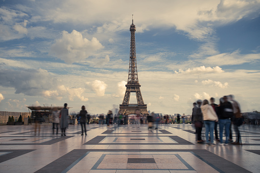 Eiffel tower, Paris symbol and iconic landmark in France, on a sunny day with clouds in the sky. Famous touristic places and romantic travel destinations in Europe. Tourism concept. Long exposure.
