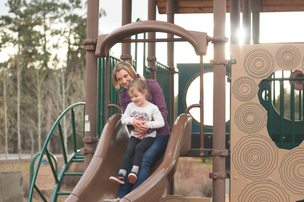 istock Mom and daughter ride down a slide together 871786570