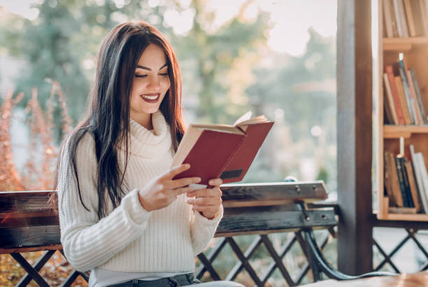istock Girl reading a book in the open library 871793318