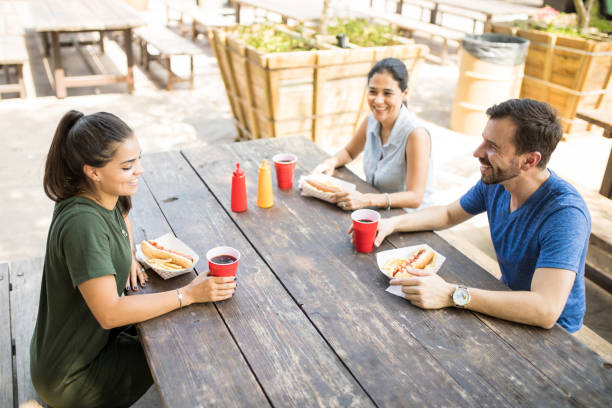 istock Three friends eating hot dogs 871820174