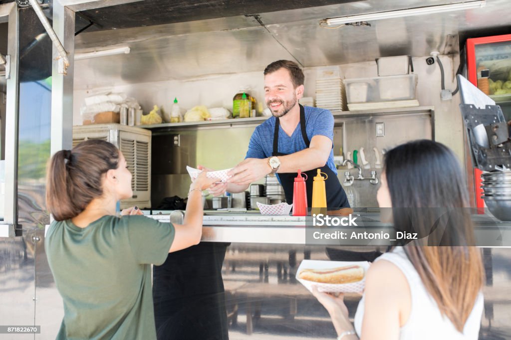 Girls buying hot dogs from food truck Rear view of a couple of women buying some hot dogs froma food truck Food Truck Stock Photo