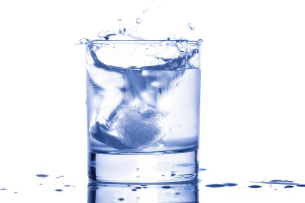 blue water splashing out of a glass with drops on a white background