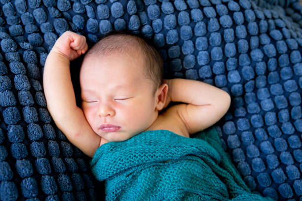 istock Sleeping Baby  wrapped in green wool blanket on dark blue textured blanket 871830416