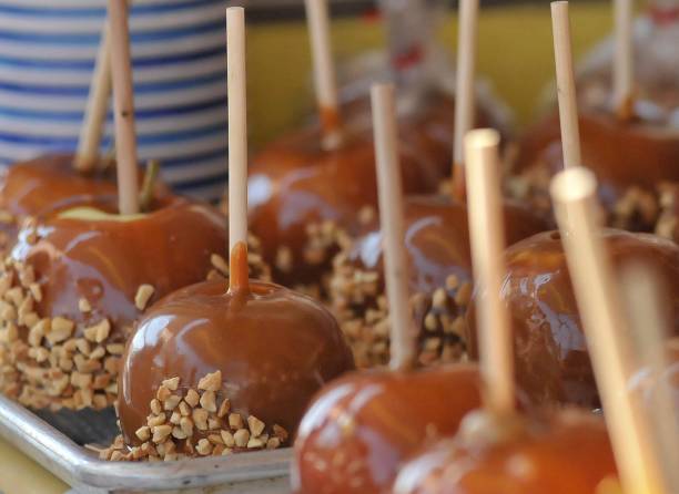 istock Carmel apples with nuts sit on a tray at a local festival. 871831664