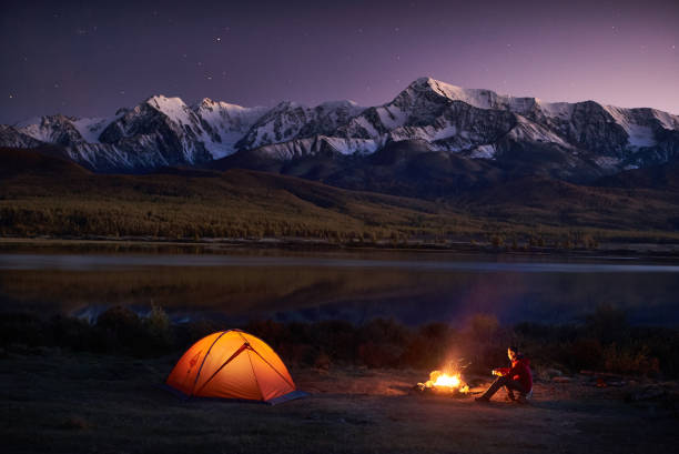 istock Man tourists sitting in the illuminated tent near campfire 871837802