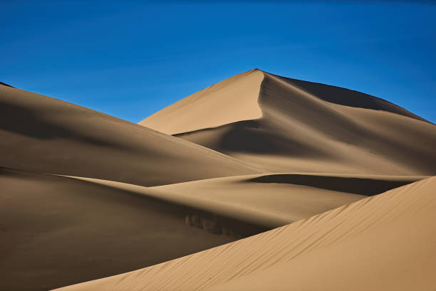 istock Smooth sand dunes in the desert, warm dry sand and blue sky 871837862