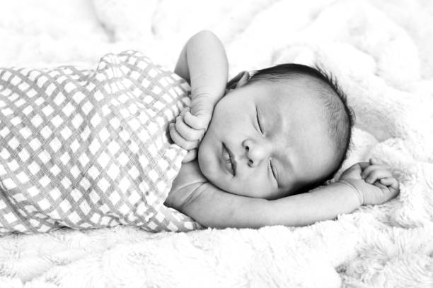 istock Black and white image of New Baby sleeping wrapped in  checked wrap 871845084